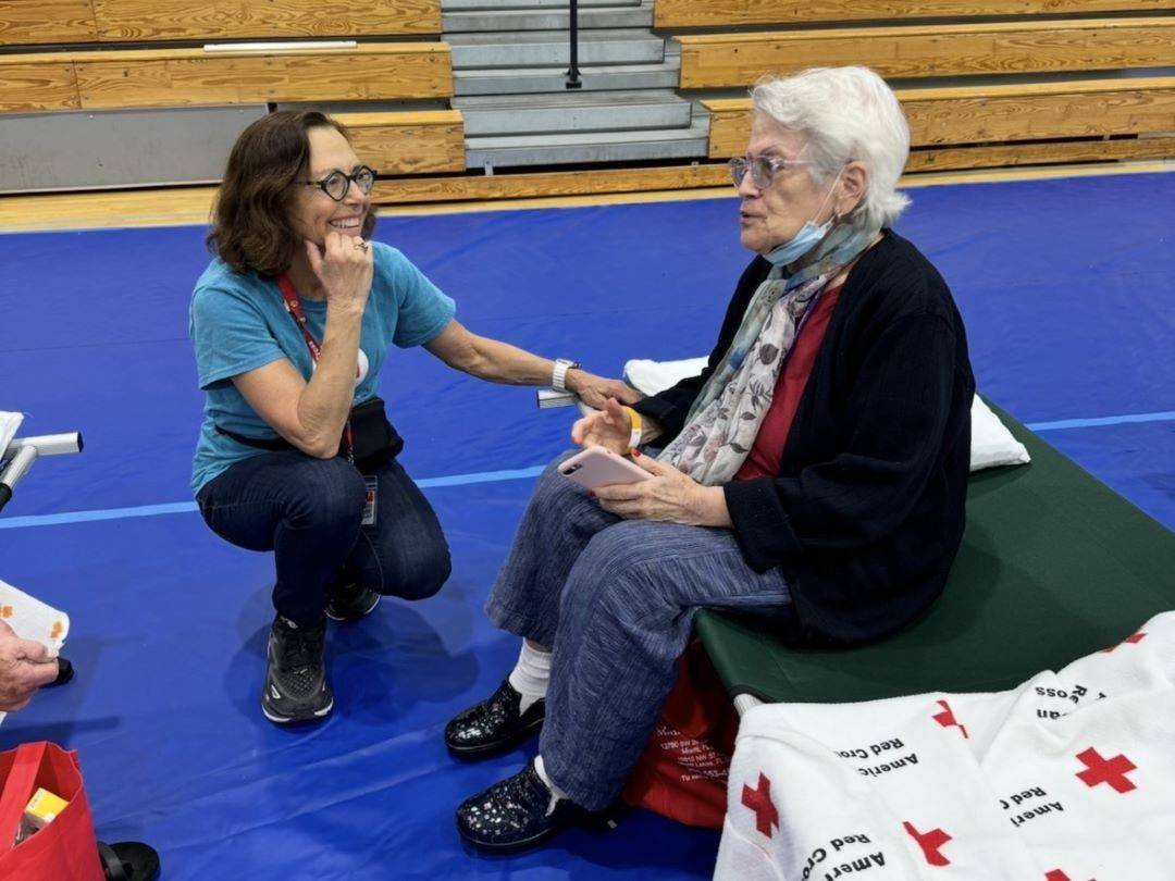 Red Cross volunteer speaks with woman in Red Cross Shelter