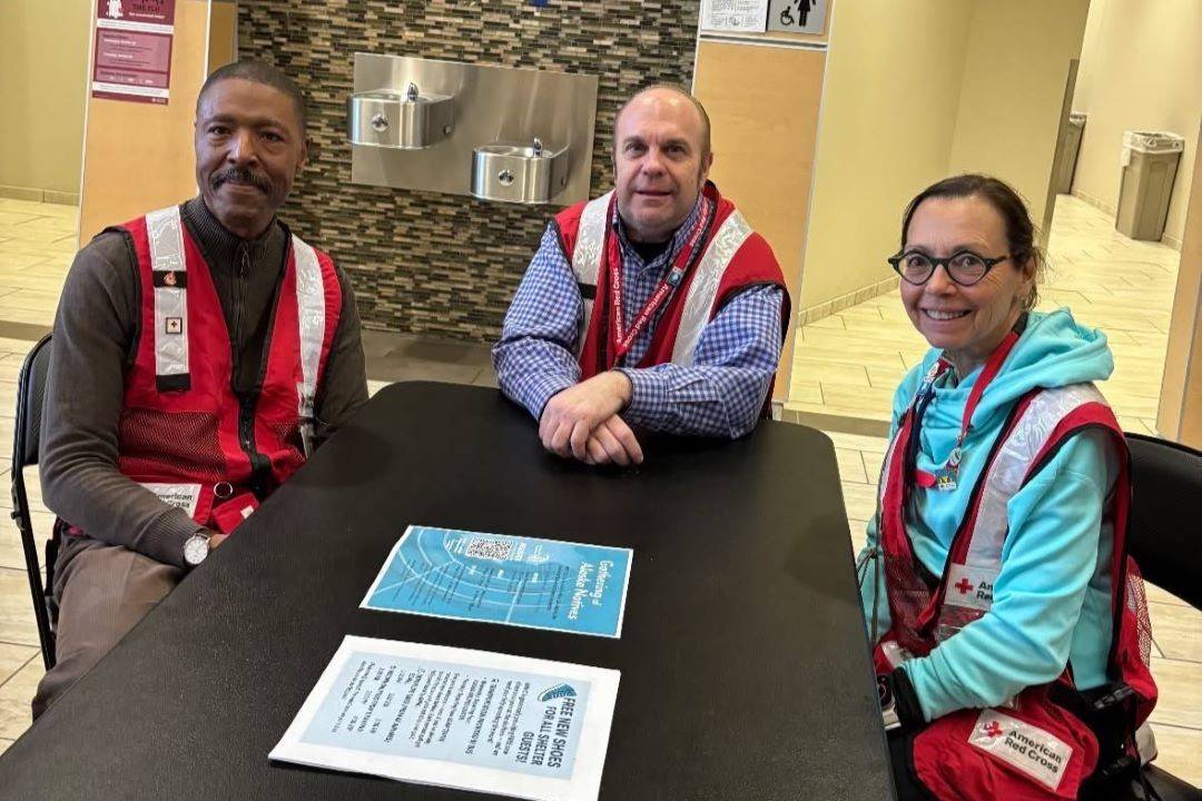 Three Red Cross volunteers sit at table with paperwork