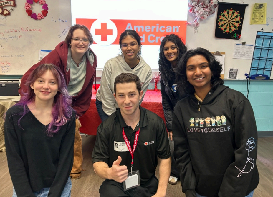 Group of young people stand in front of projector screen with Red Cross logo