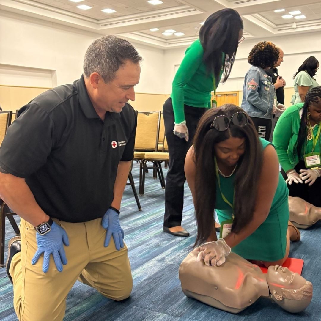 instructor watches as woman practices cpr on mannequin
