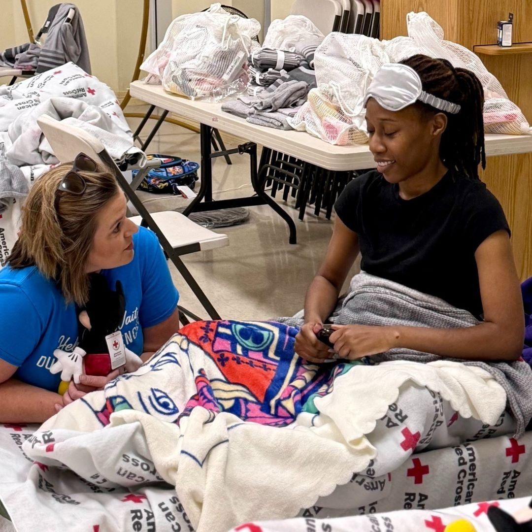 red cross volunteer talks with woman in shelter
