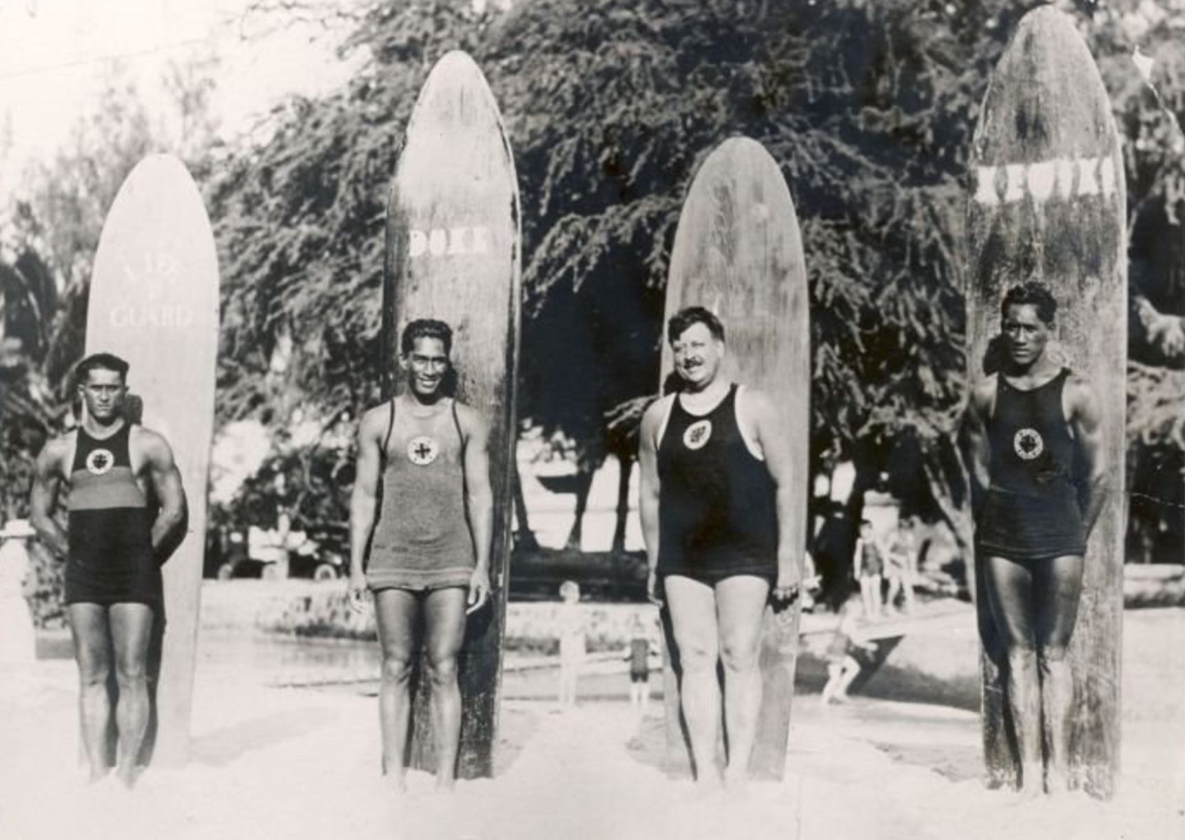 black and white photo of surfers in front of their surfboards