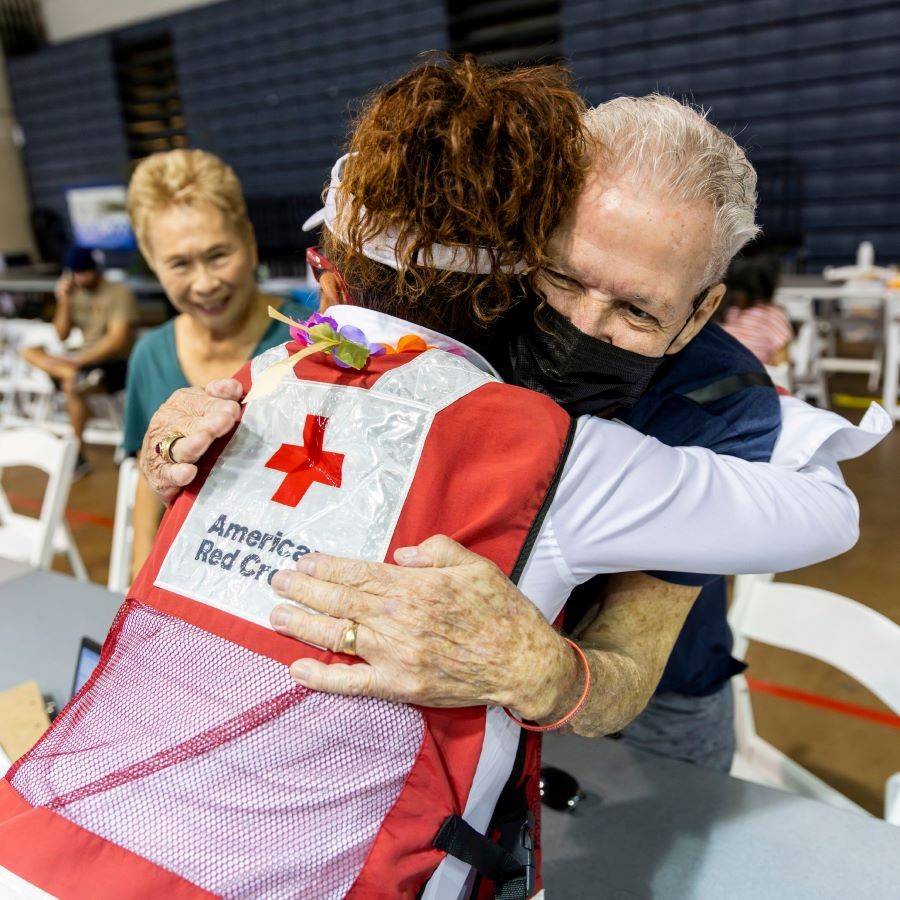red cross volunteer hugging client in shelter