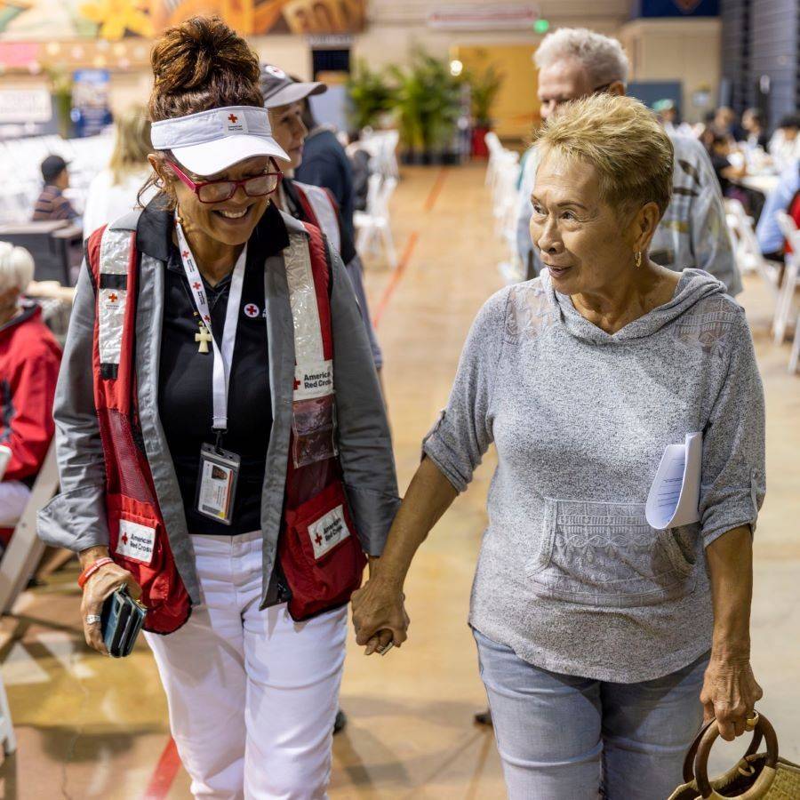 red cross volunteer holding hand of client in shelter