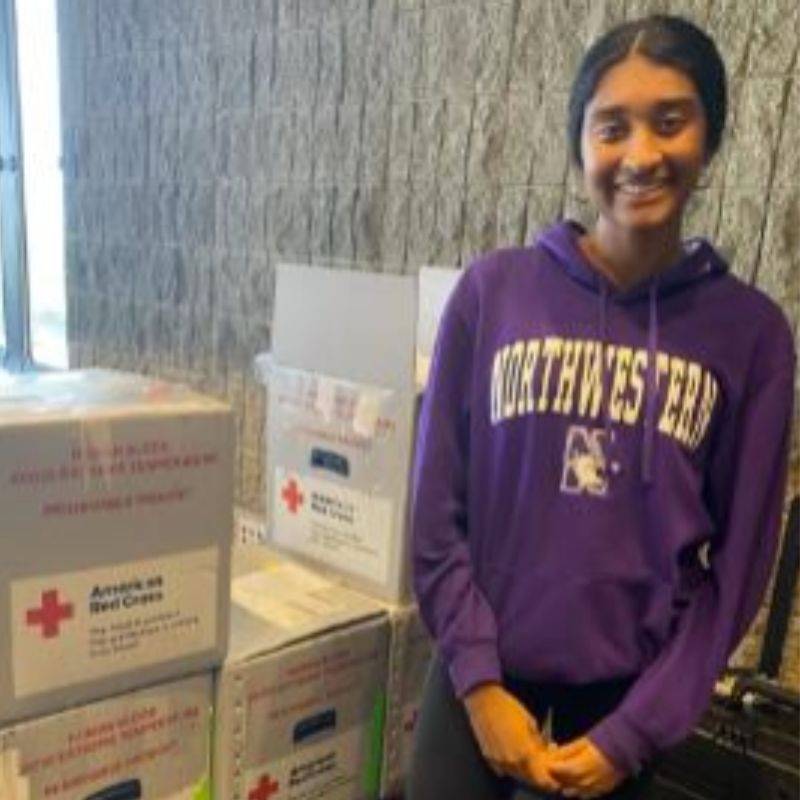 aparnaa standing in front of red cross storage boxes