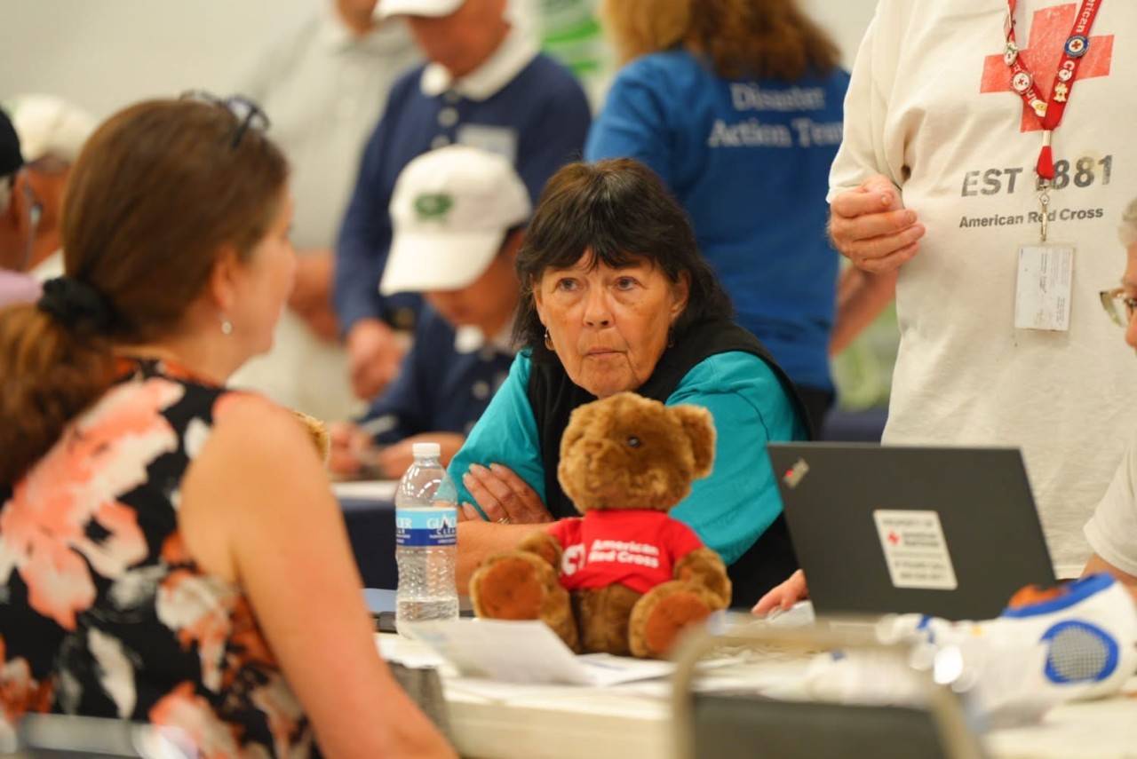 Woman sits at table with small stuffed bear