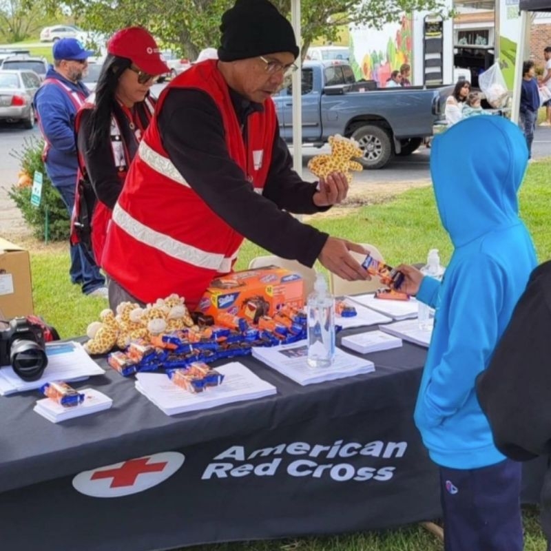 danny diaz at red cross table booth speaking with child