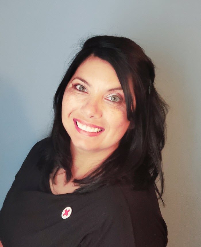 woman smiling with black shirt and red cross pin