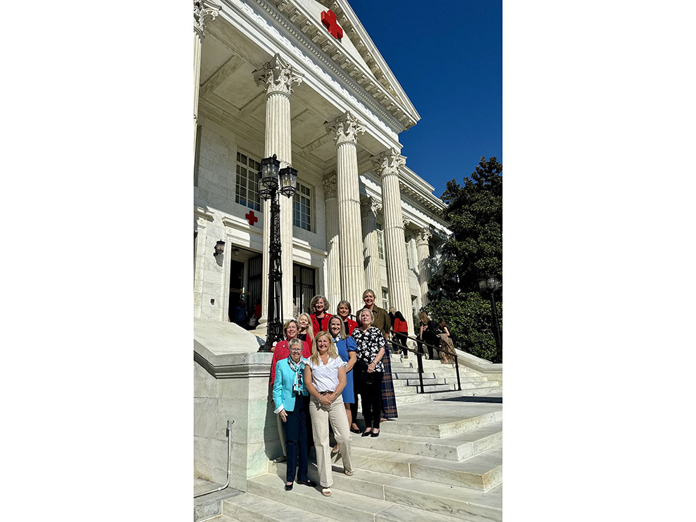 Nine Tiffany Circle members take a group photo outside a Red Cross building.