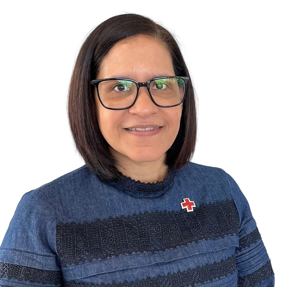 photo of woman in blue sweater with a red cross pin