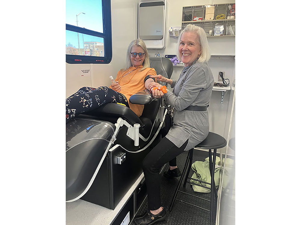 Person sitting in chair and donating blood in a mobile blood mobile.