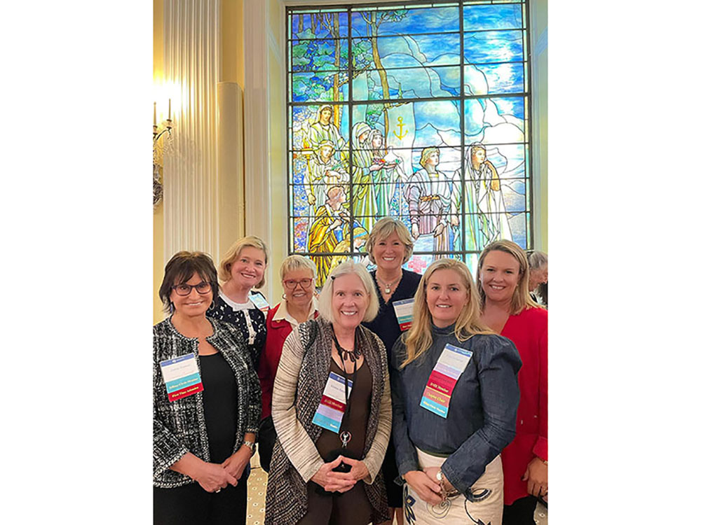 Tiffany Circle members group photo in front of a stained glass window mural.