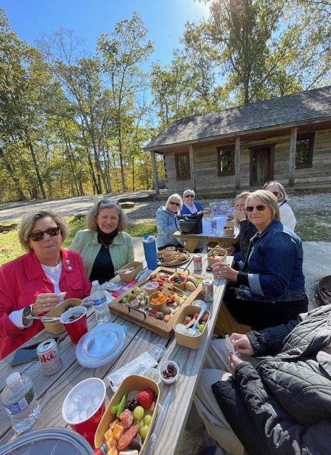 Group of women sitting at a table having a picnic.