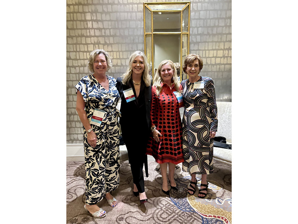 Four Tiffany Circle members in business clothing and wearing name tags take a group photo.