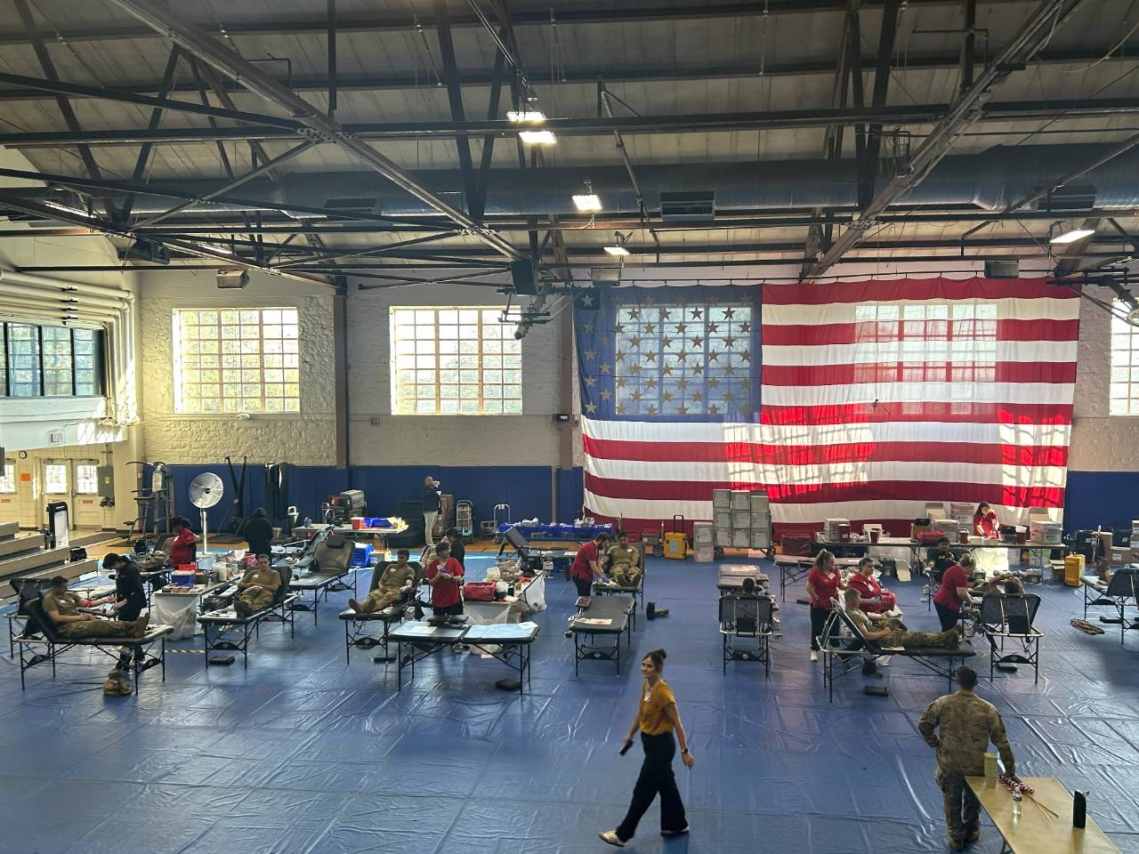 Wide view of inside of building with multiple blood donation chairs set up and members of the military donating blood