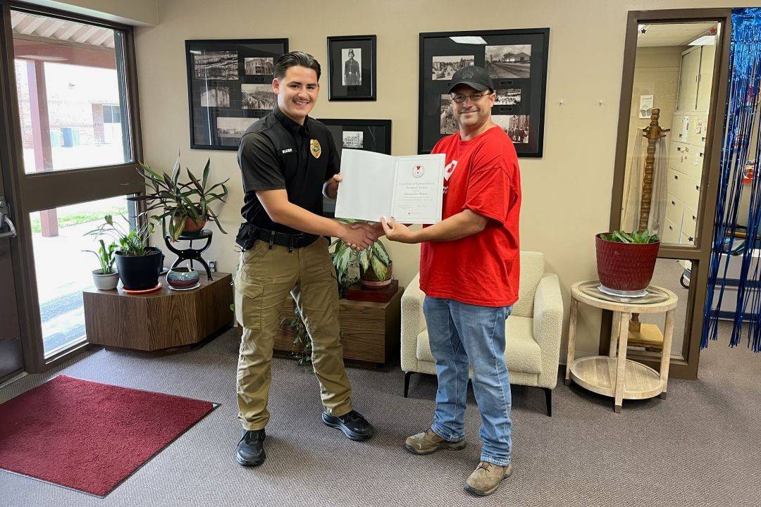 Officer stands next to Red Cross volunteer holding Red Cross award