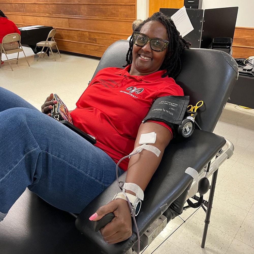 a woman sitting in a chair and donating blood.