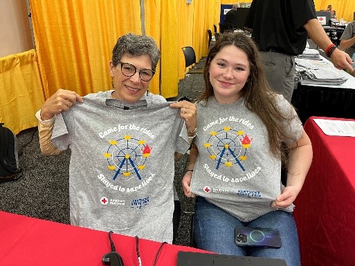 Two red cross volunteers holding up a shirt