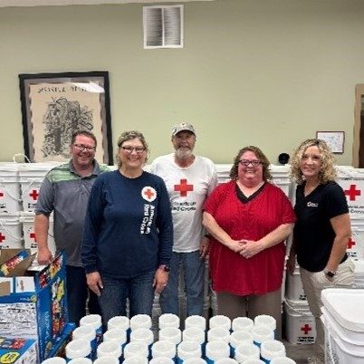 group of red cross volunteers stand with clean up kits
