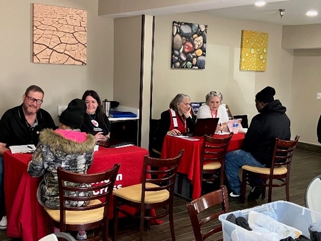 red cross volunteers sit across tables from people