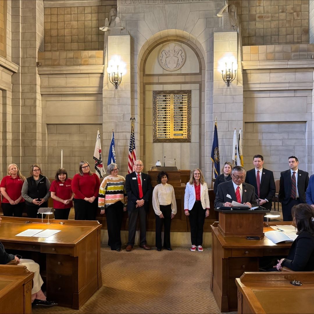 group of red cross volunteers stand with governor 