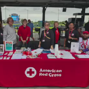 group of red cross volunteers stand behind table