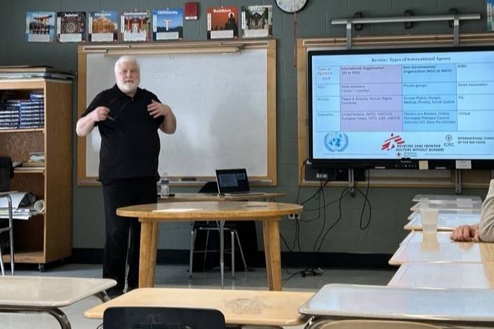 Man stands in front of screen and speaks to room