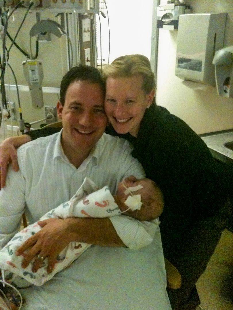 Parents smile while holding newborn baby in hospital
