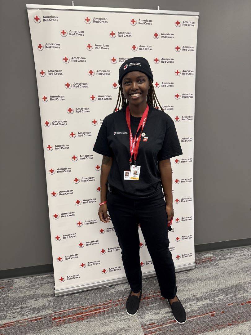 Woman stands in front of Red Cross banner
