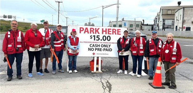 Group of Red Cross volunteers standing in a parking lot with a "Park Here" sign.