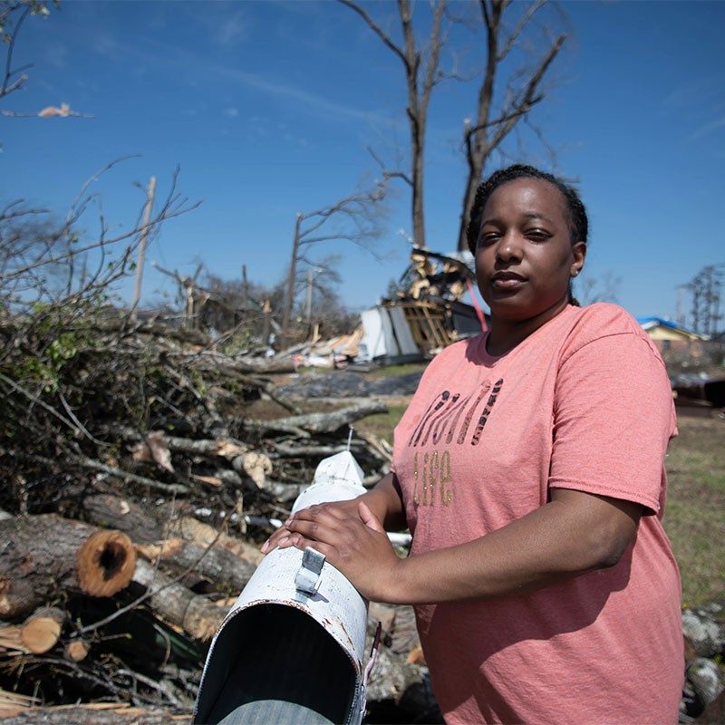 Woman standing in front of destroyed homes.