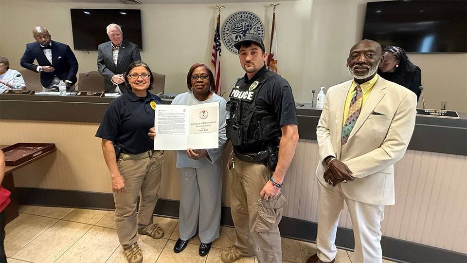 Officer Cody Bolt holding the American Red Cross Certificate of Extraordinary Personal Action with other officers and staff in the room.