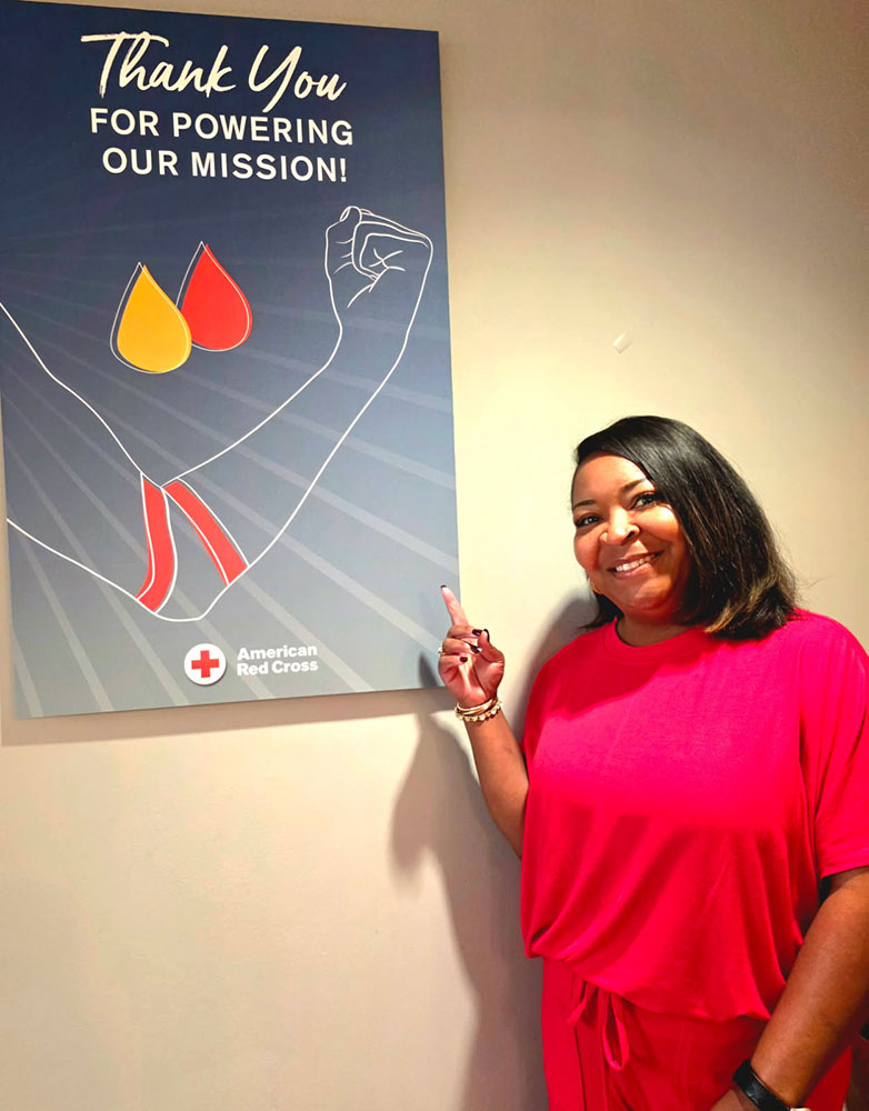 Tillie Smith pointing at a blood donation thank you poster on a wall.