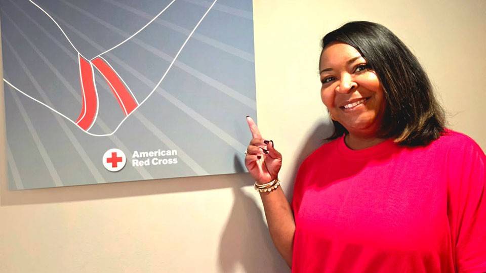 Tillie Smith pointing at a blood donation thank you poster on a wall.