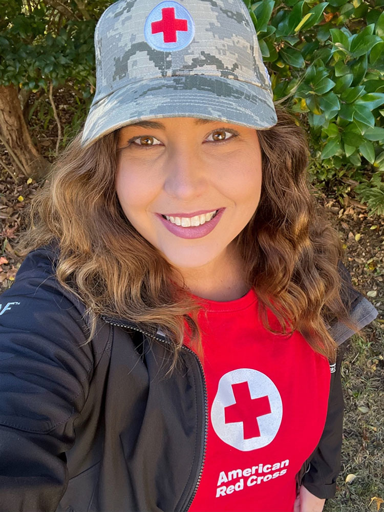 Brittney Rabens, wearing a red cross shirt and hat, takes a selfie.