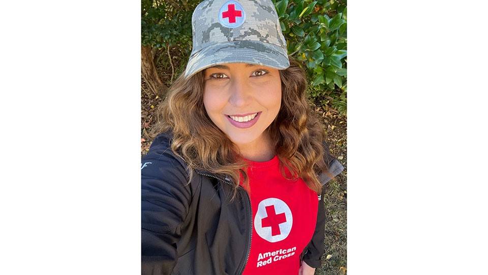 Brittney Rabens, wearing a red cross shirt and hat, takes a selfie.