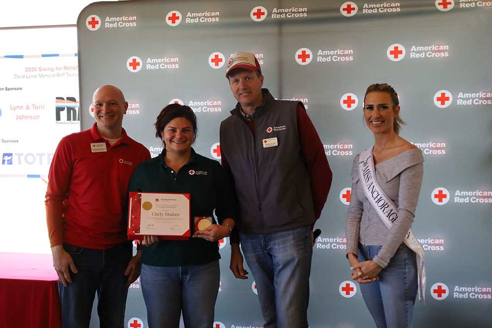 Carly Stuber holding her Red Cross award while standing next to three people at a Red Cross event.