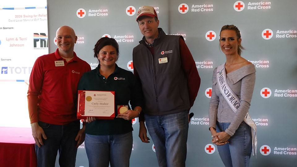 Carly Stuber holding her Red Cross award while standing next to three people at a Red Cross event.