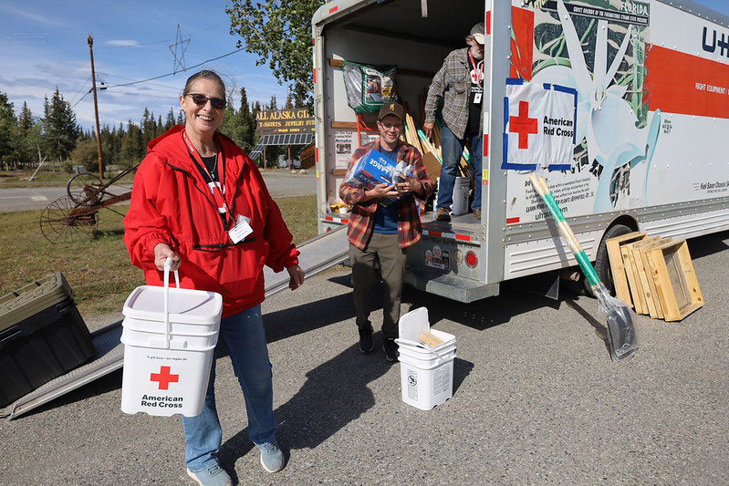 Red Cross volunteers unloading disaster supplies from a moving van.