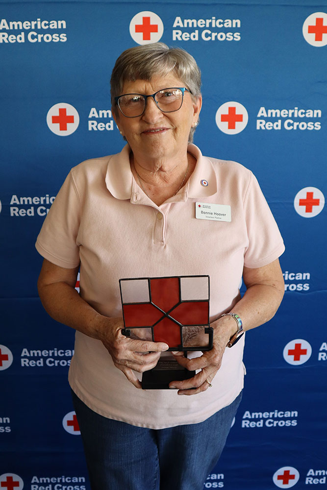 Bonnie Hoover holding the New Mexico Chapter’s Disaster Cycle Services Volunteer of the Year Award at a Red Cross event.