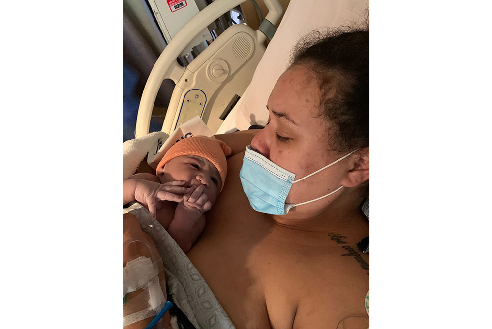 Angelena Fly wearing a mask while holding her baby in a hospital bed.