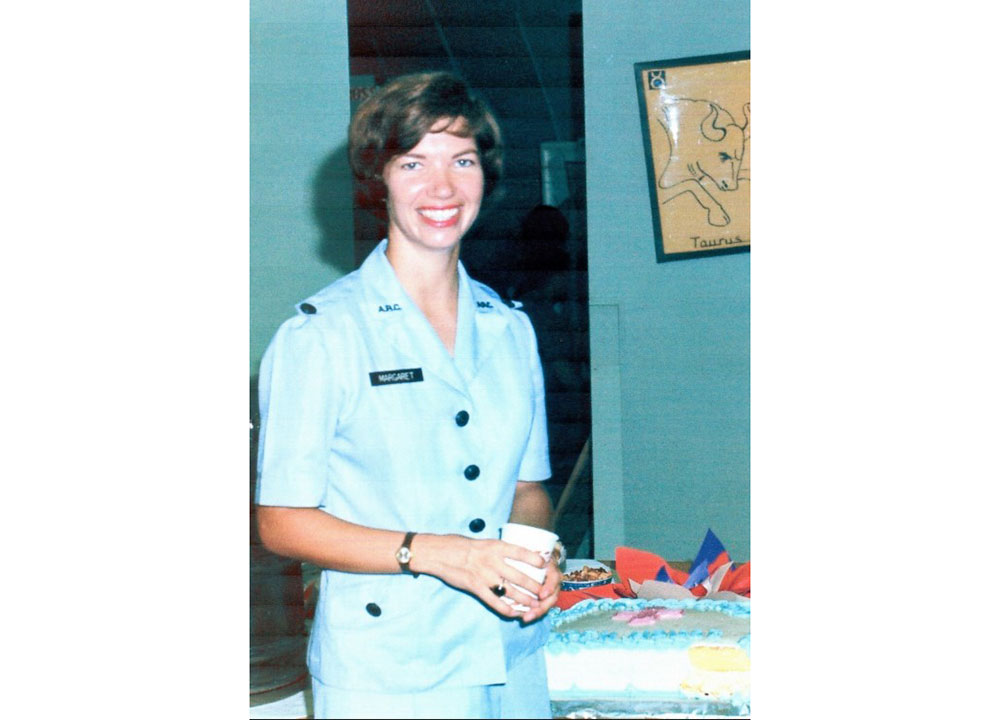 American Red Cross Donut Dolly volunteer, Margaret “Maggie" Goodrich Hodge in uniform, holding a cup and smiling for camera.