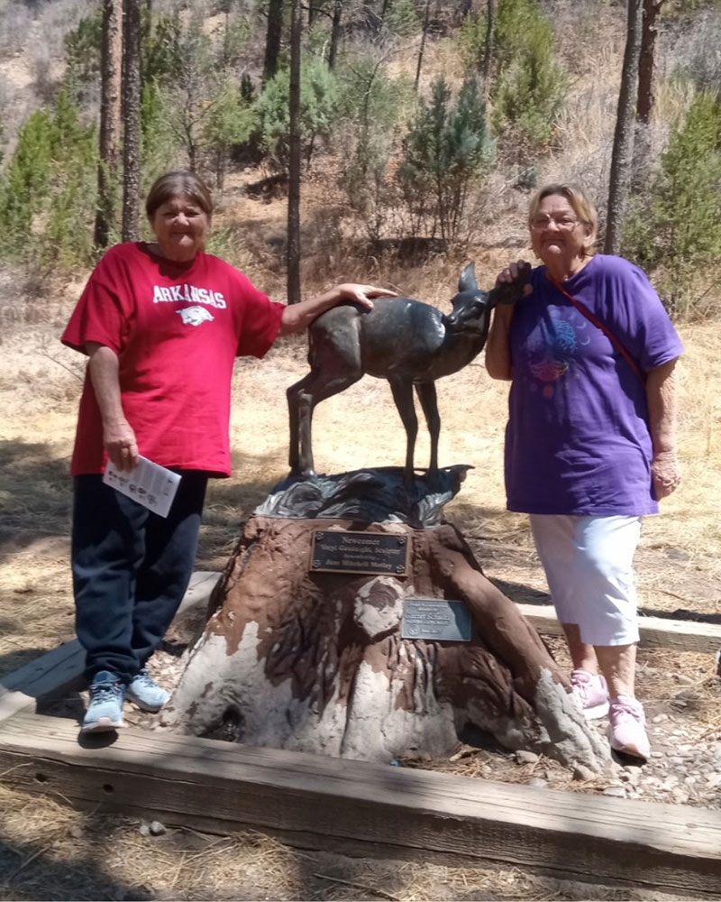 Flo Harris and Irma Easley standing next to a deer statue.