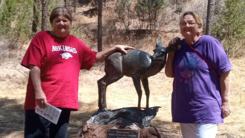 Flo Harris and Irma Easley standing next to a deer statue.