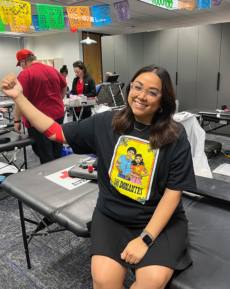 Karolina Peraza holds up her arm and shows bandage after donating blood.