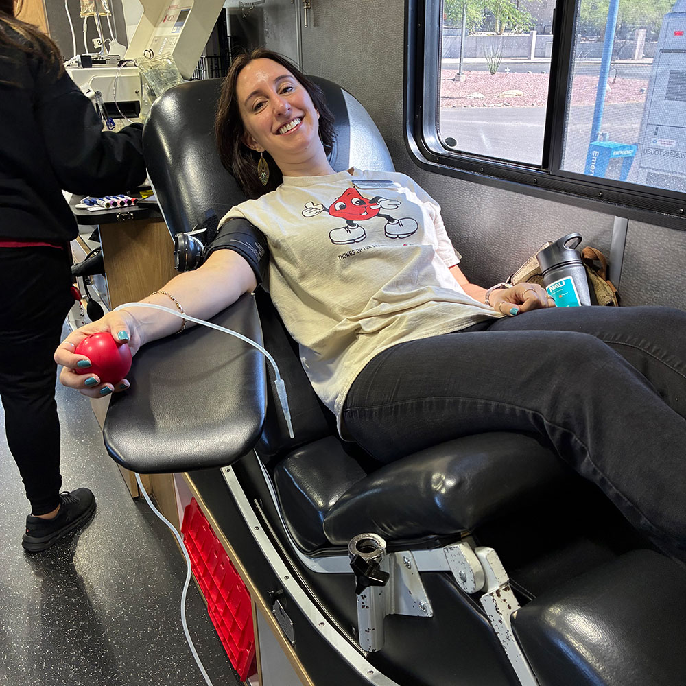 Melissa Lyapustina sitting in a chair in the red cross bloodmobile and donating blood.