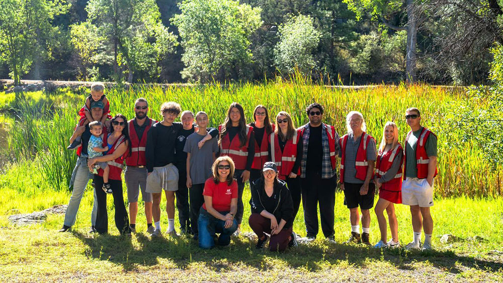 a group of Red Cross volunteers standing in a green grassy aread with trees in the background.