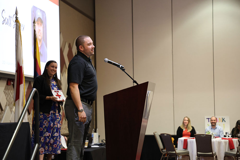 Scott Salzer speaking at a podium to a room full of people.