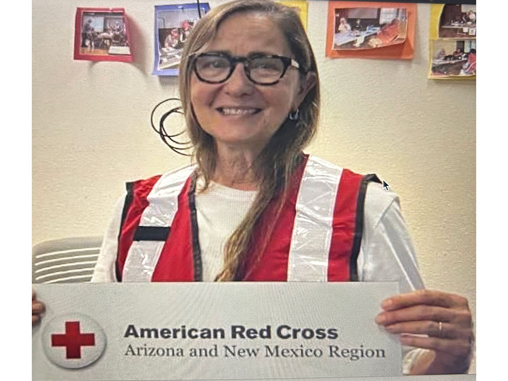 Sofia Theard in a Red Cross vest holding a American Red Cross Arizona and New Mexico Region logo.