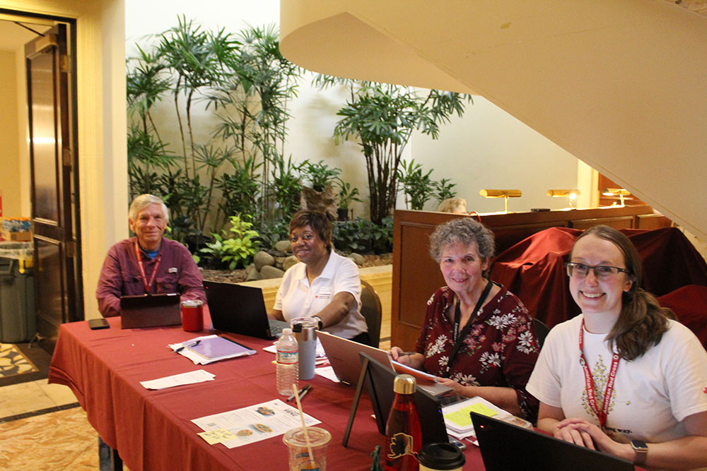 Red Cross volunteers sitting at a table with laptops.